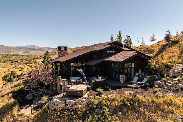rear view of house featuring a patio, a chimney, and a mountain view