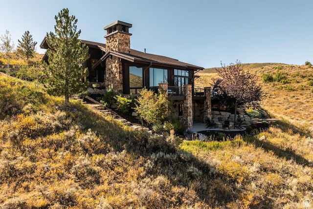 exterior space featuring a chimney, a patio area, and stone siding