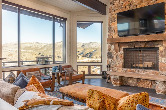 living room featuring a fireplace, beam ceiling, and wood finished floors
