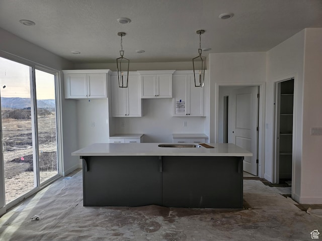 kitchen with a mountain view, pendant lighting, a center island with sink, and white cabinets