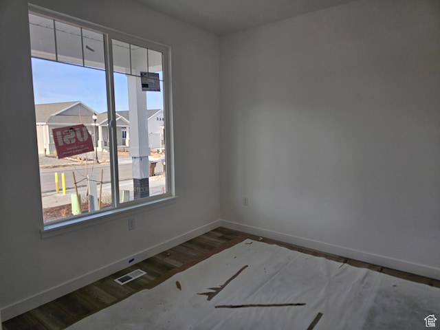 spare room featuring hardwood / wood-style flooring and plenty of natural light