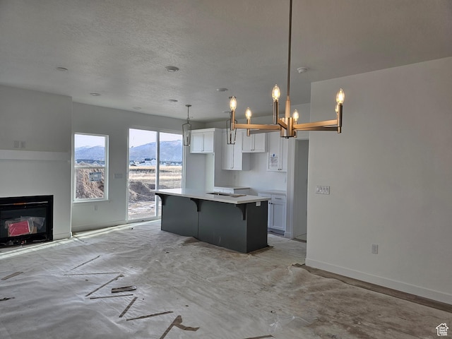 kitchen with a kitchen breakfast bar, decorative light fixtures, white cabinetry, a mountain view, and a kitchen island