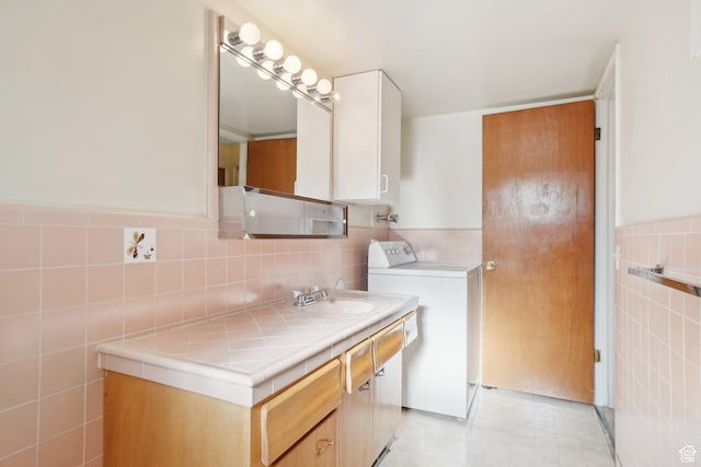 bathroom featuring washer / clothes dryer, vanity, and tile walls