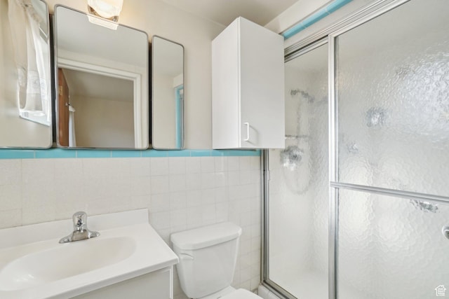 bathroom with vanity, backsplash, toilet, tile walls, and an enclosed shower