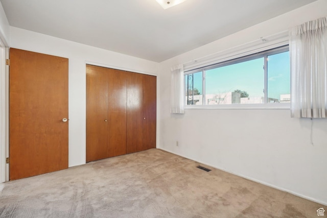 unfurnished bedroom featuring light carpet and two closets