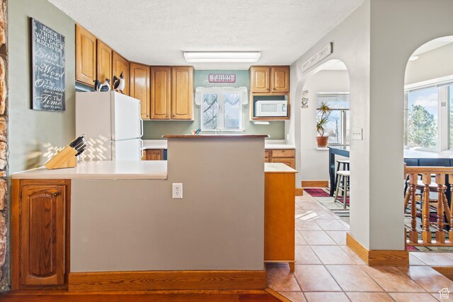 110 N 400 E, Glenwood, UT 84730 - kitchen featuring white appliances, light countertops, a peninsula, a textured ceiling, and arched walkways
