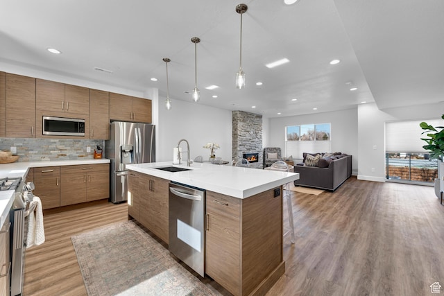 1618 S Main St Unit 3, Salt Lake City, UT 84115 - kitchen featuring sink, hanging light fixtures, stainless steel appliances, a fireplace, and a center island with sink