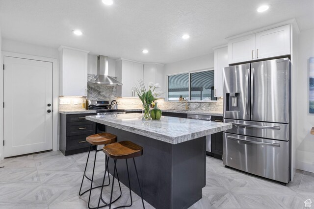 1578 E Delaware Ln S, Holladay, UT 84117 - kitchen featuring white cabinetry, a center island, wall chimney range hood, tasteful backsplash, and appliances with stainless steel finishes