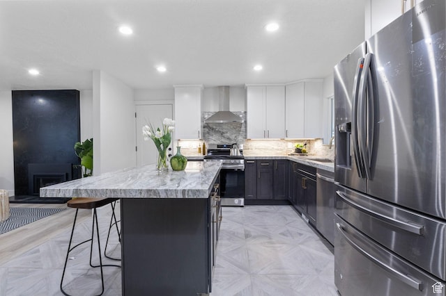1578 E Delaware Ln S, Holladay, UT 84117 - kitchen featuring wall chimney exhaust hood, stainless steel appliances, a kitchen island, a breakfast bar, and white cabinets