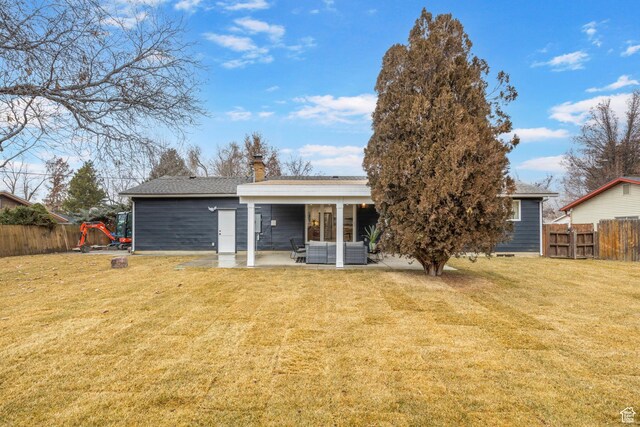 back of house with a lawn and a patio