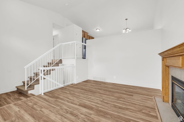 256 Bubbling Brook Ln, Draper, UT 84020 - unfurnished living room featuring vaulted ceiling, an inviting chandelier, wood-type flooring, and a tiled fireplace