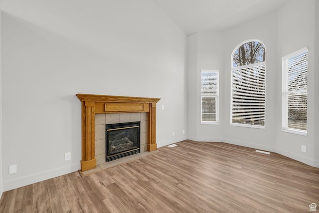 256 Bubbling Brook Ln, Draper, UT 84020 - unfurnished living room with light wood-type flooring, a wealth of natural light, and a tiled fireplace