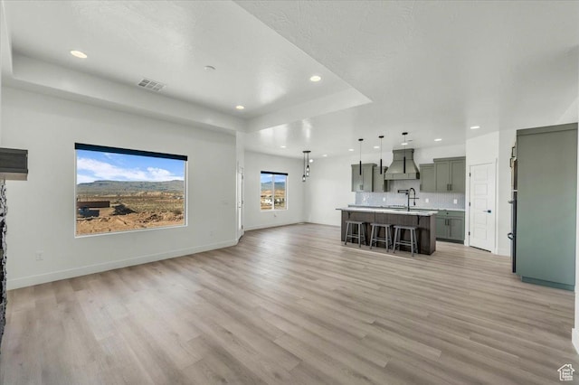 6148 S Square Top Ln, St George, UT 84790 - unfurnished living room featuring light wood-type flooring, sink, and a tray ceiling