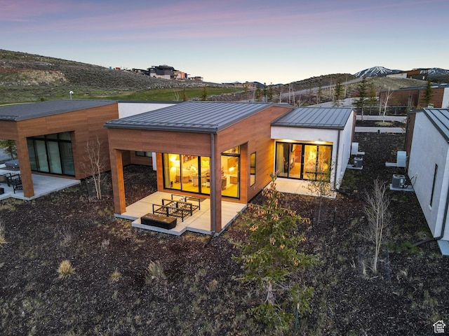 6242 Double Deer Loop, Park City, UT 84098 - back of house at dusk with a standing seam roof, metal roof, a patio, and central AC unit