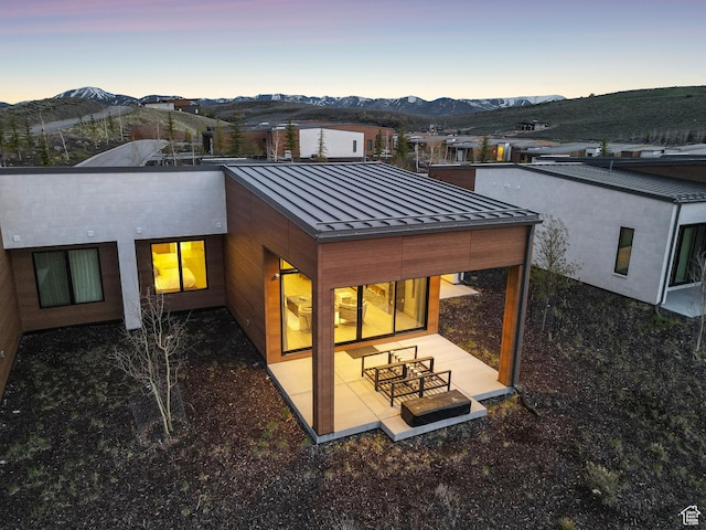 6242 Double Deer Loop, Park City, UT 84098 - back of house at dusk featuring a standing seam roof, a mountain view, metal roof, and a patio area