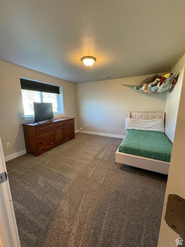 unfurnished bedroom featuring a textured ceiling and dark carpet