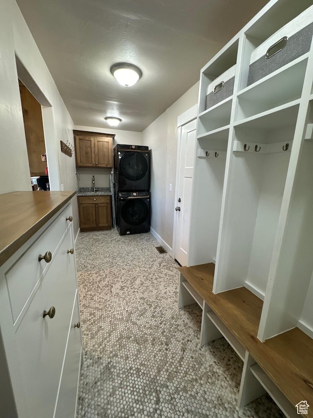 mudroom with sink and stacked washing maching and dryer