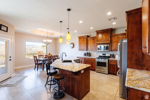 437 N Northstar Dr, St George, UT 84770 - kitchen with a breakfast bar, sink, light stone counters, appliances with stainless steel finishes, and an island with sink