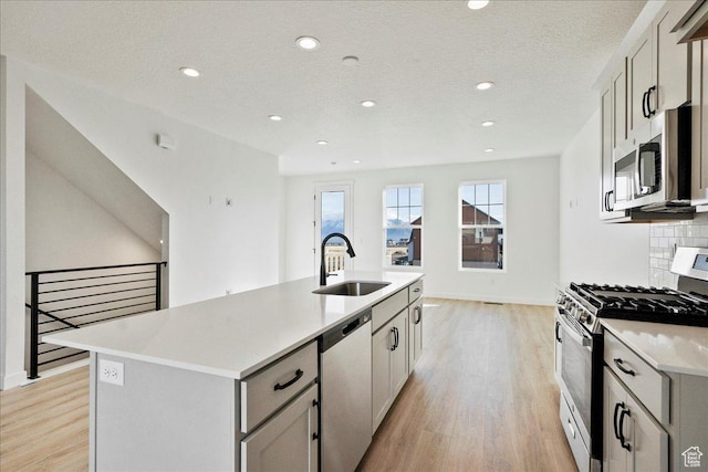 7029 W S Jordan Pkwy Unit 380, South Jordan, UT 84009 - kitchen featuring appliances with stainless steel finishes, a sink, light wood-style flooring, a center island with sink, and recessed lighting