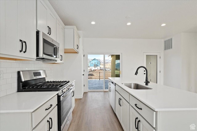 7029 W S Jordan Pkwy Unit 380, South Jordan, UT 84009 - kitchen featuring appliances with stainless steel finishes, a sink, light wood-type flooring, decorative backsplash, and light countertops