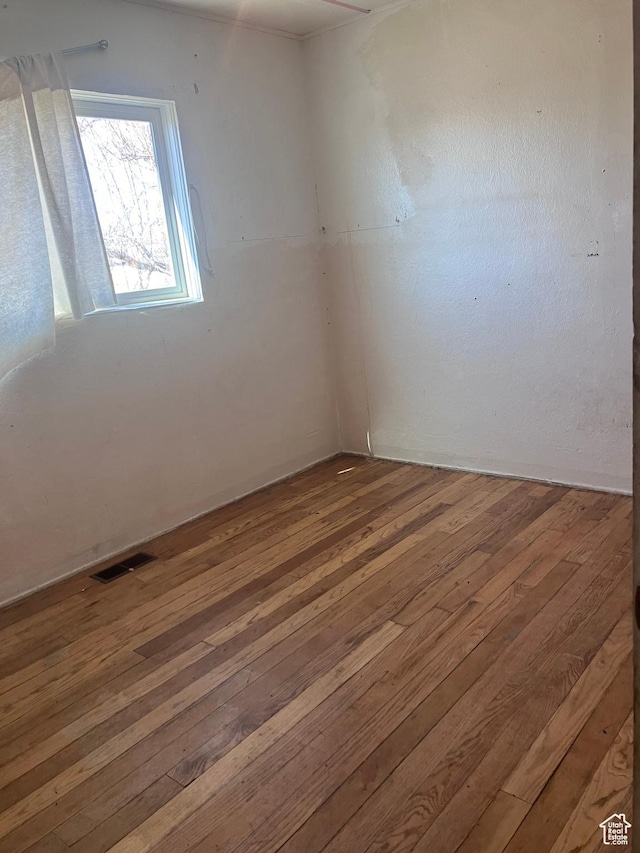 unfurnished room featuring hardwood / wood-style flooring and visible vents