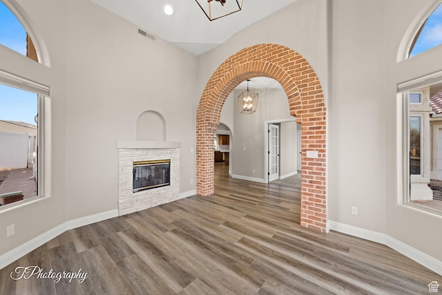 unfurnished living room with hardwood / wood-style floors and a stone fireplace