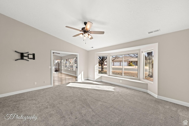 unfurnished living room featuring plenty of natural light, ceiling fan, light colored carpet, and lofted ceiling