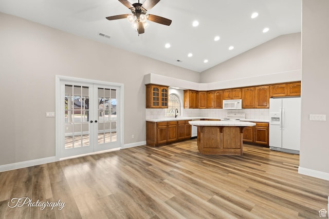 kitchen with french doors, white appliances, ceiling fan, sink, and a kitchen island