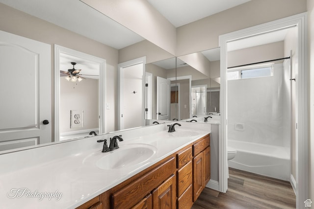 full bathroom with vanity, ceiling fan, hardwood / wood-style flooring, washtub / shower combination, and toilet