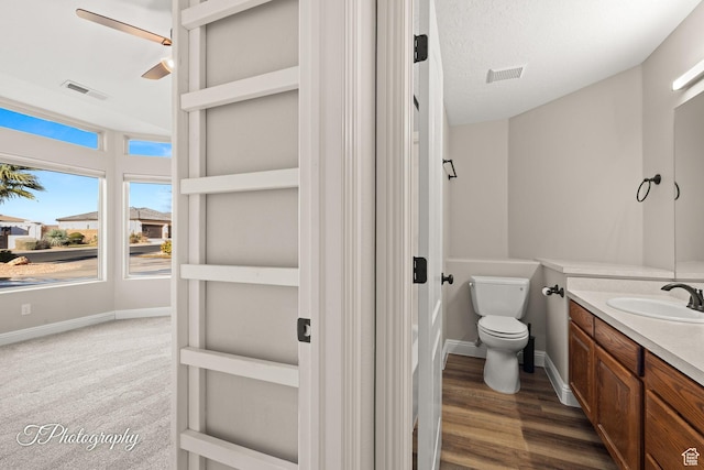 bathroom featuring vanity, a textured ceiling, ceiling fan, wood-type flooring, and toilet
