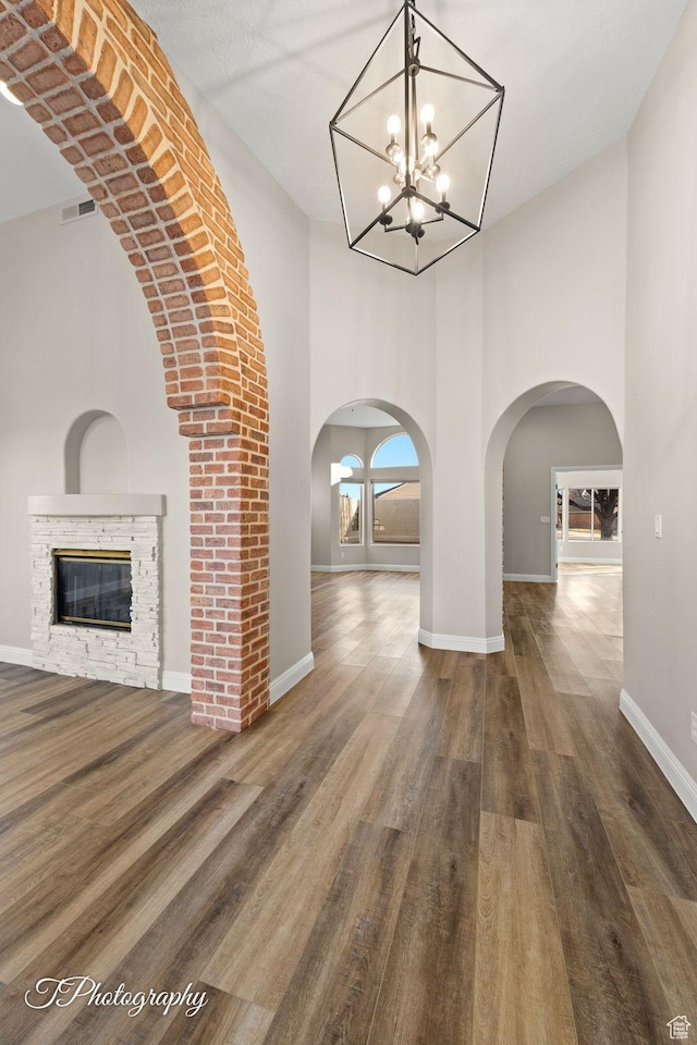 corridor featuring a towering ceiling, dark hardwood / wood-style floors, and a notable chandelier