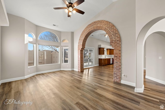 unfurnished living room with ceiling fan, hardwood / wood-style floors, vaulted ceiling, and sink