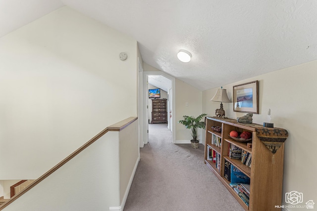 hallway with a textured ceiling, baseboards, lofted ceiling, and carpet floors