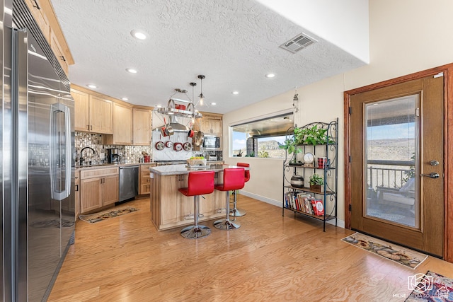 kitchen featuring built in appliances, light wood-style floors, light brown cabinetry, and a healthy amount of sunlight