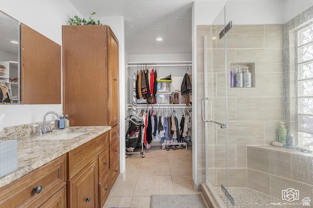 bathroom with tile patterned floors, a walk in closet, vanity, and a stall shower
