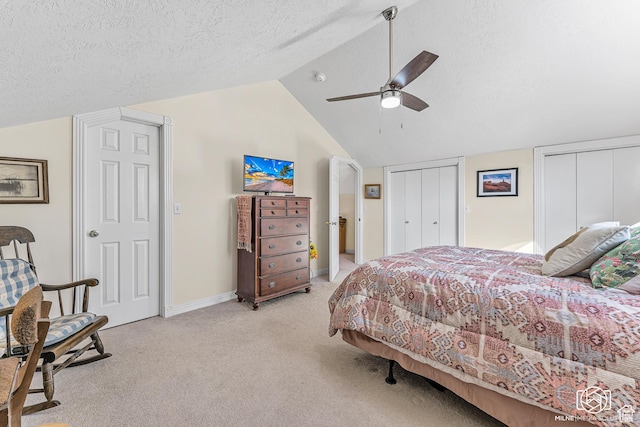 bedroom featuring ceiling fan, light colored carpet, vaulted ceiling, multiple closets, and baseboards