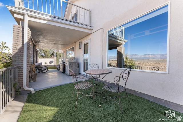 view of patio / terrace with fence, a balcony, grilling area, and a mountain view