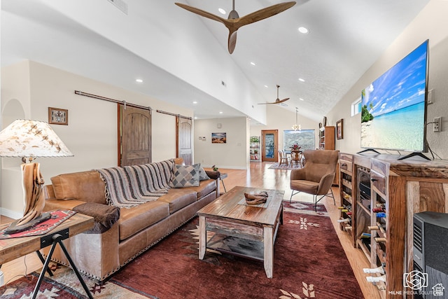 living room with ceiling fan with notable chandelier, recessed lighting, high vaulted ceiling, and a barn door