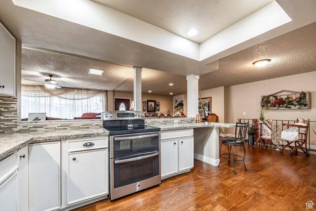 395 W 400 N Unit 39, Bountiful, UT 84010 - kitchen featuring decorative columns, wood finished floors, a textured ceiling, white cabinetry, and range with two ovens