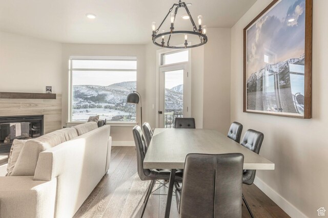 dining area featuring a mountain view, hardwood / wood-style floors, a fireplace, and a notable chandelier