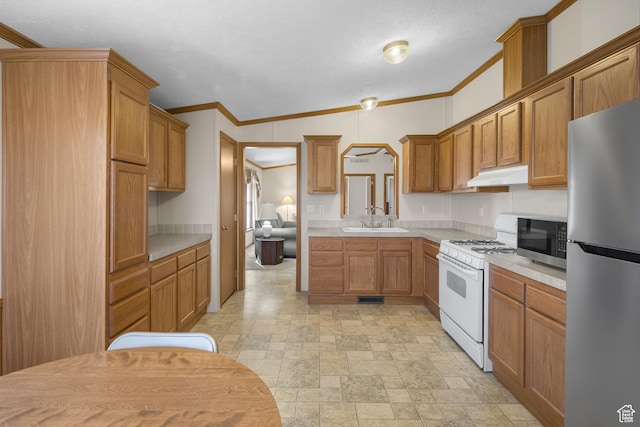 kitchen with sink, vaulted ceiling, ornamental molding, a textured ceiling, and stainless steel appliances