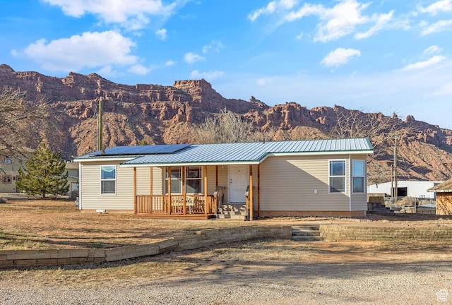view of front of house featuring a mountain view, covered porch, and solar panels
