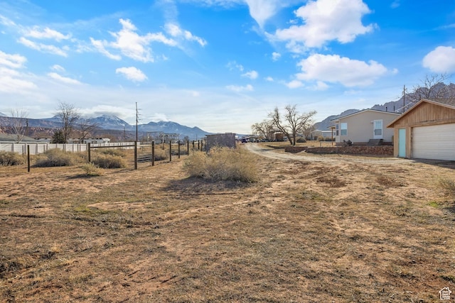 view of yard featuring a mountain view, a rural view, an outdoor structure, and a garage