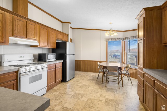 kitchen with stainless steel fridge, ornamental molding, white range with gas cooktop, pendant lighting, and a chandelier