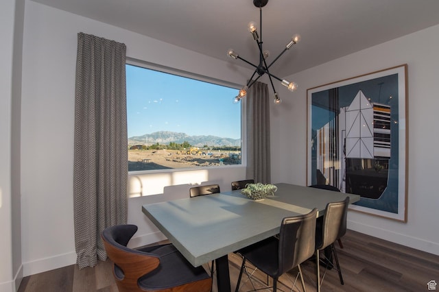 dining room featuring an inviting chandelier, wood finished floors, a mountain view, and baseboards
