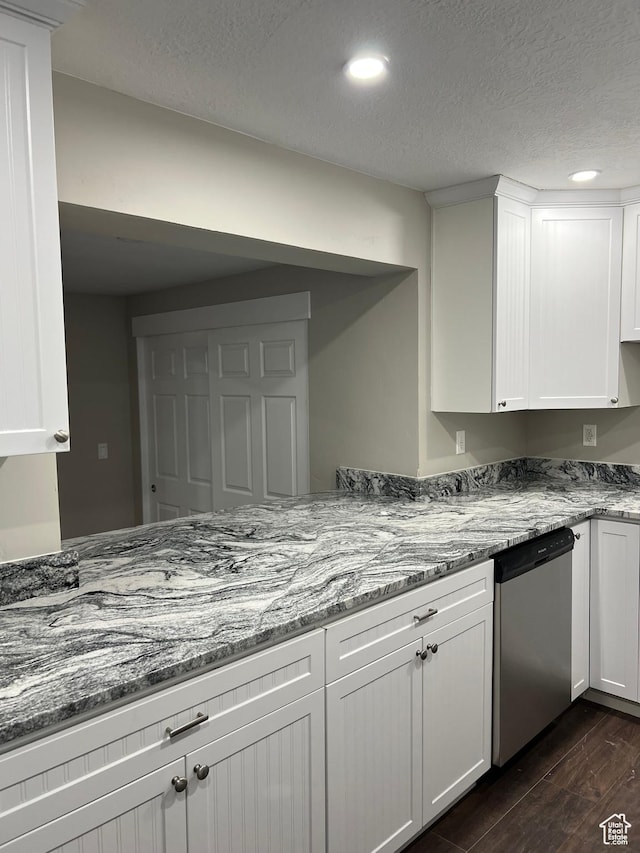 kitchen with dishwasher, light stone countertops, white cabinetry, and a textured ceiling