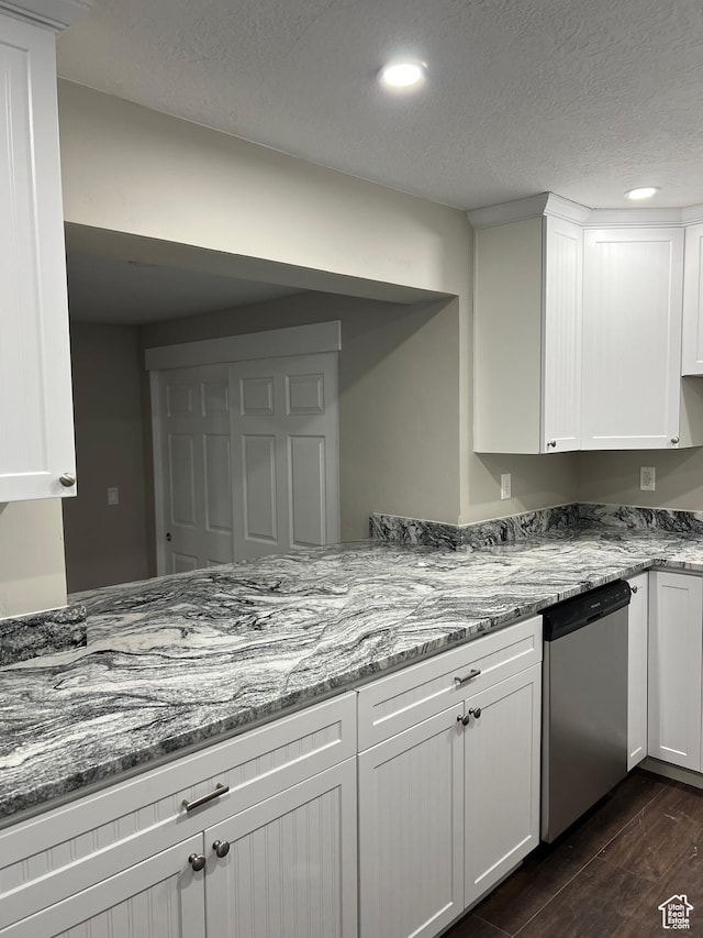 kitchen featuring stainless steel dishwasher, white cabinets, light stone counters, and a textured ceiling