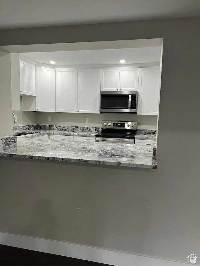 kitchen with sink, stainless steel appliances, white cabinetry, and light stone counters