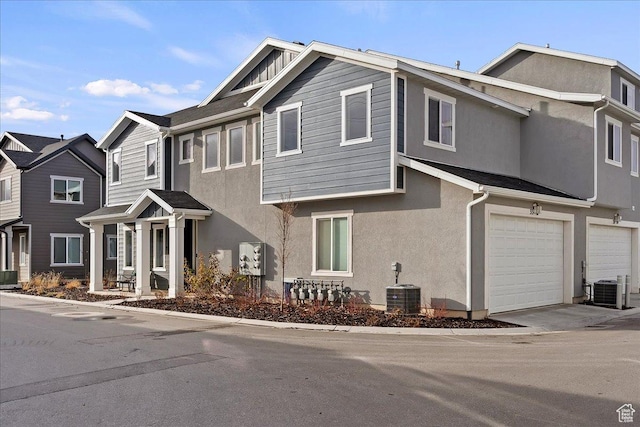 multi unit property with stucco siding, central AC unit, and an attached garage