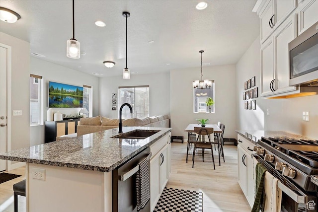 kitchen featuring dark stone countertops, white cabinetry, a sink, stainless steel appliances, and recessed lighting